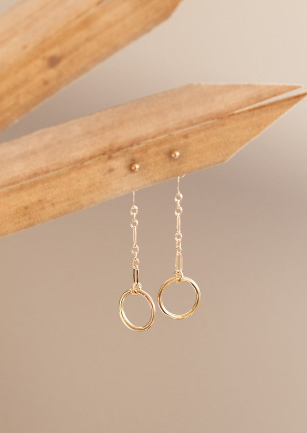 Drop earrings from Hello Adorn in the Monday Backdrop style where a stud earring is attached to a chain drop earring with a circle attached to the end of the chain.