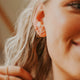 Small gold earrings in Tiny Bar stud style by Hello Adorn styled with twist earrings and gold hoop earrings.