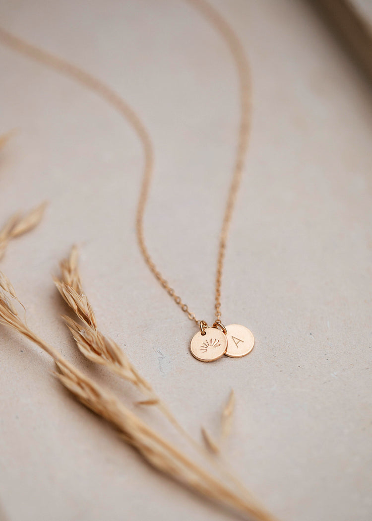 Gold stamped jewelry attached to a gold initial necklace by Hello Adorn.