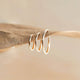 Gold infinity hoop earrings by Hello Adorn showing three difference sizes.