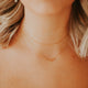 A simple necklace layering idea shown with a paperclip necklace attached to a chain necklace and a chain linked necklace in a choker necklace style from Hello Adorn, paired with a hoop charm earring.