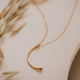 A crescent moon necklace with a hammered gold pendant in a mini-moon shape handmade by Hello Adorn.