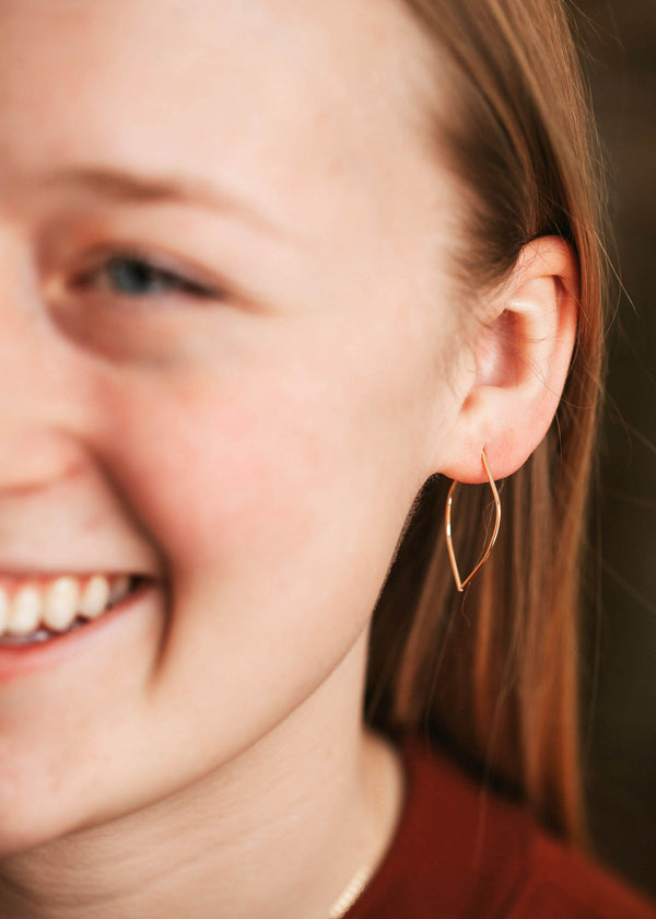 A gold threader earring shown worn in an ear in a petal earring design handmade by Hello Adorn.