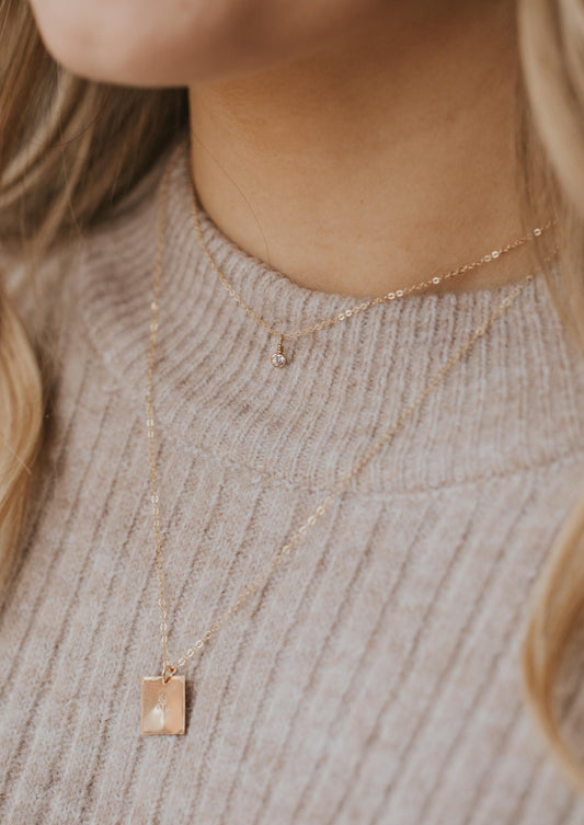 A simple necklace layering idea that pairs a necklace with pendant and a flower with a stone necklace from Hello Adorn, a simple everyday jewelry look.