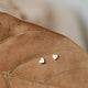 Tiny heart earrings shown in 14k gold fill by Hello Adorn in a stud earring style.