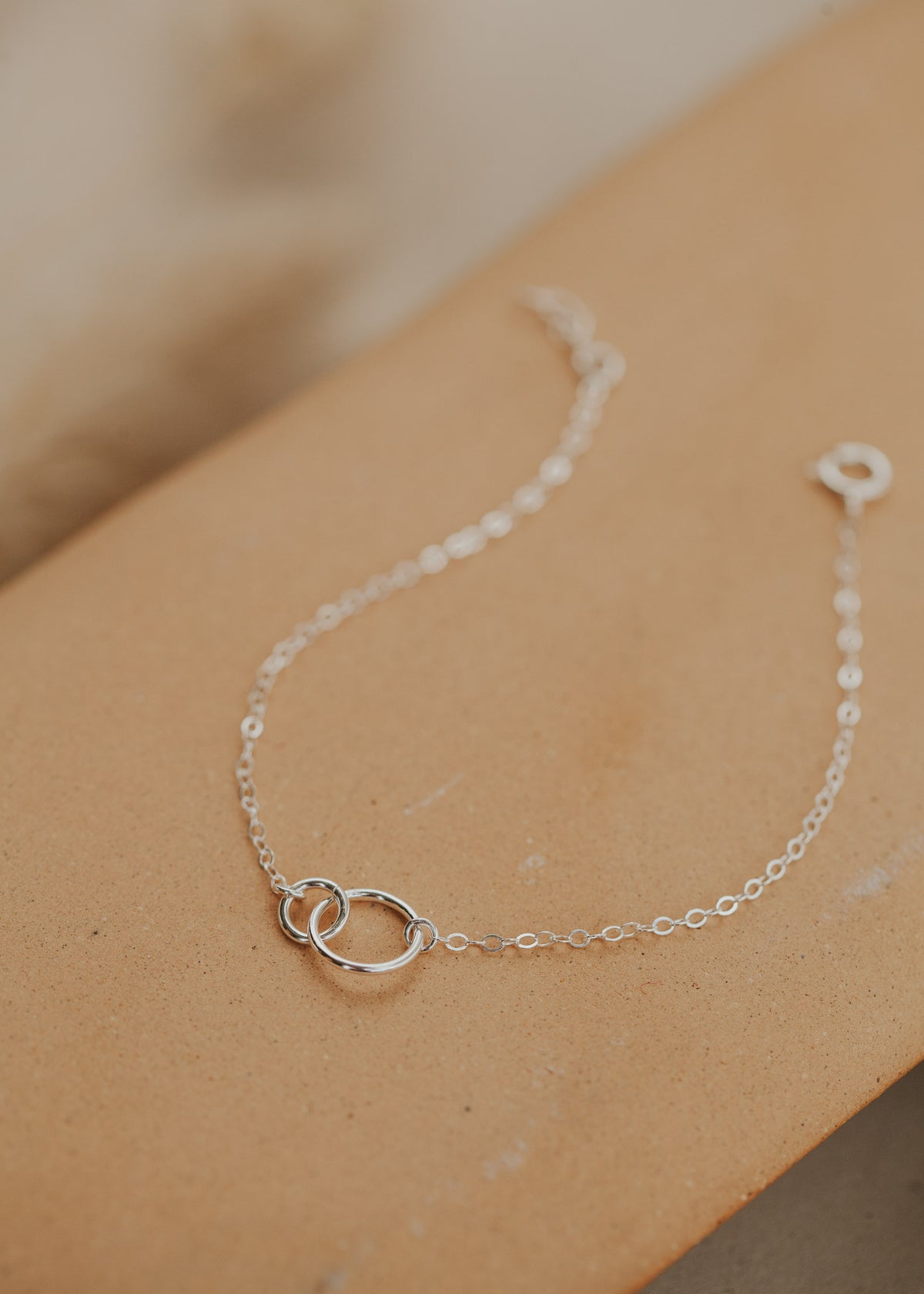 A sterling silver dainty bracelet in Tiny Links Bracelet by Hello Adorn, an interlocking circle necklace to add to any bracelet stack idea.